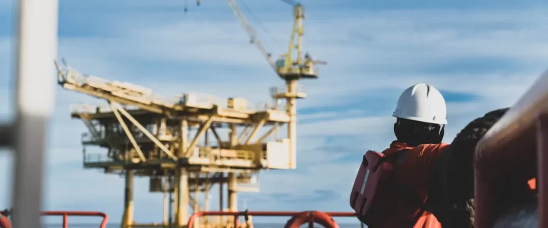 offshore worker looking into the horizon and an oil rig