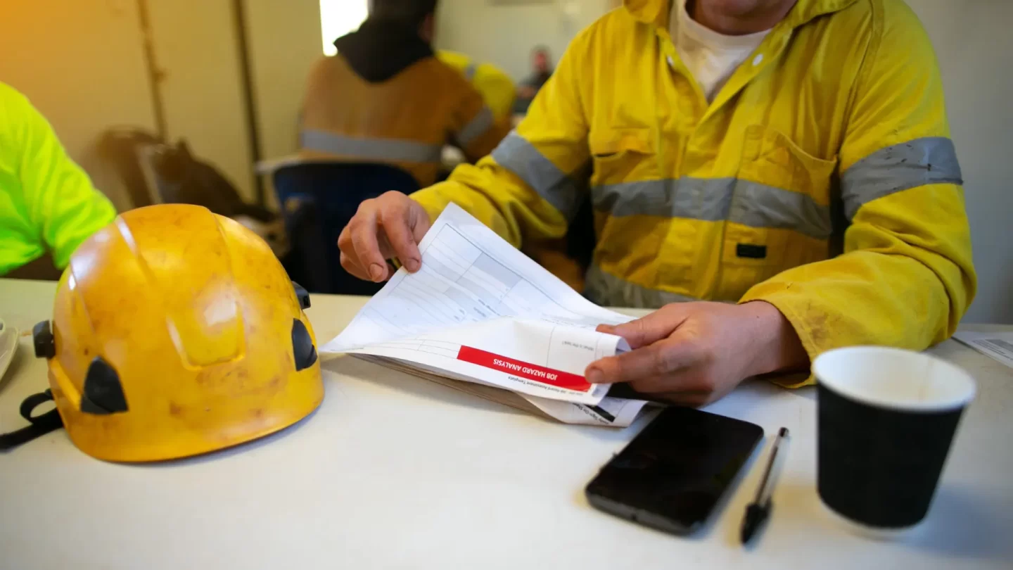 Profesionales del medio ambiente leyendo un documento de seguridad con un casco sobre la mesa