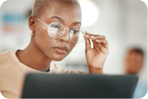 A professional woman adjusting her glasses while working on a computer, depicting strategic talent consulting services.